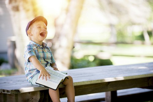 Little boy laughing and holding a book