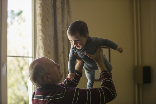 Grandfather smiling and lifting a smiling baby