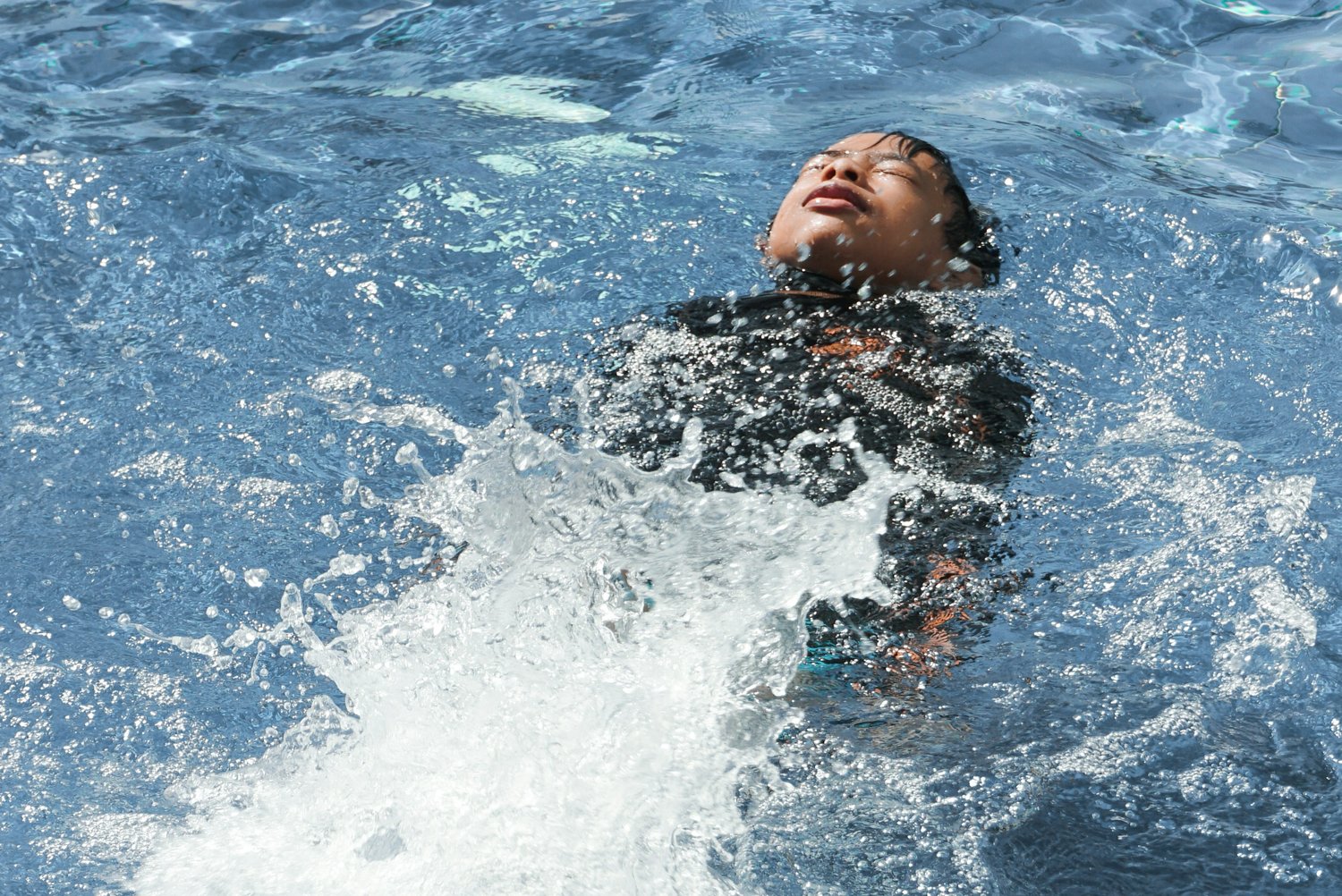 Young child swimming on their back in a pool